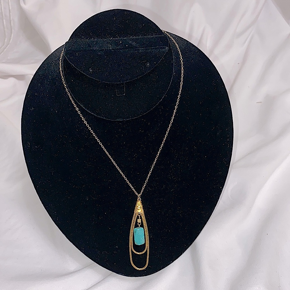 Gold tone necklace with teardrop pendant with turquoise stone on the middle.